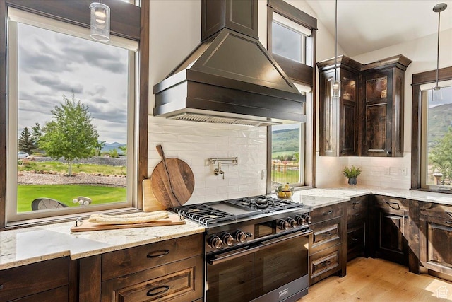 3749 N Eagle Ridge Dr E, Eden, UT 84310 - kitchen featuring double oven range, custom range hood, dark brown cabinetry, decorative backsplash, and light stone counters