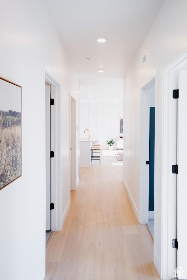 hall with light wood-type flooring and baseboards