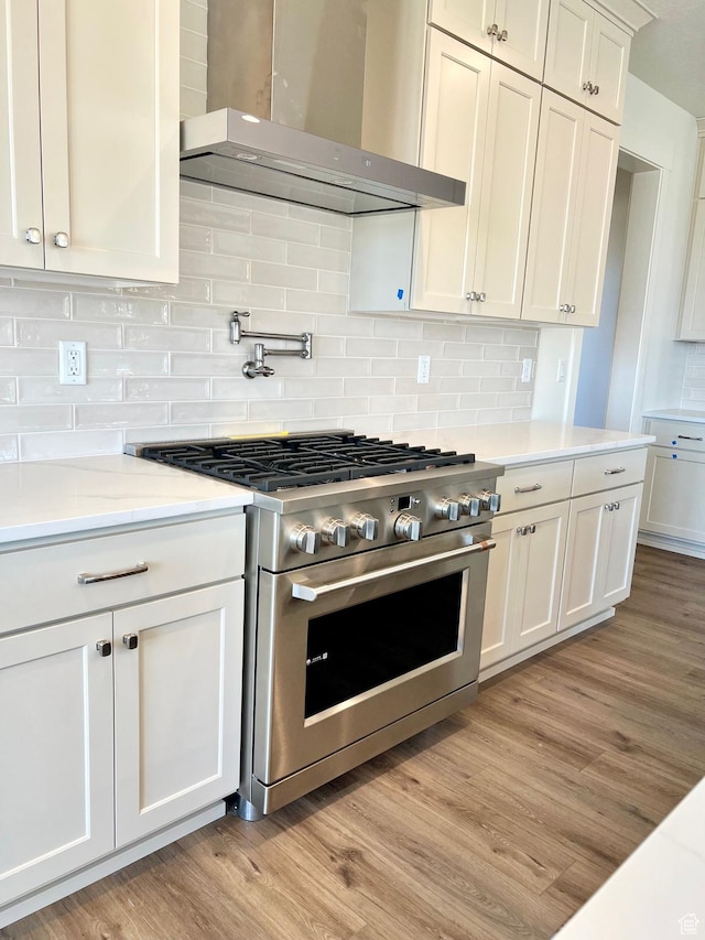 11121 S Bingham Rim Rd W Unit 5-425, South Jordan, UT 84009 - kitchen with stainless steel range, wall chimney range hood, light wood-style floors, backsplash, and white cabinets