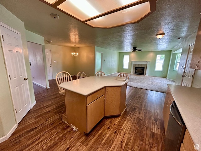 kitchen featuring a tile fireplace, dark wood-style floors, a breakfast bar, light countertops, and ceiling fan