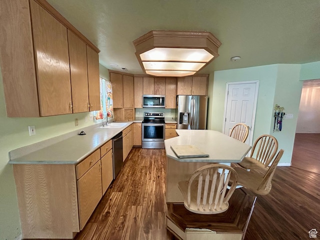 kitchen featuring stainless steel appliances, dark wood finished floors, light countertops, a center island, and a sink