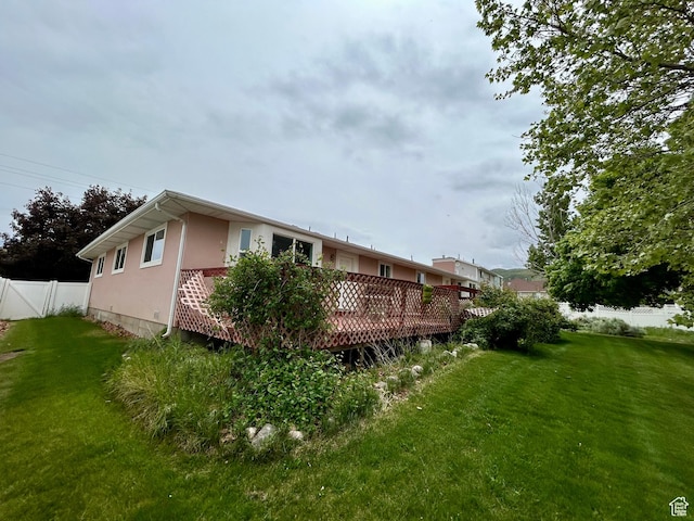 rear view of property featuring a wooden deck and stucco siding