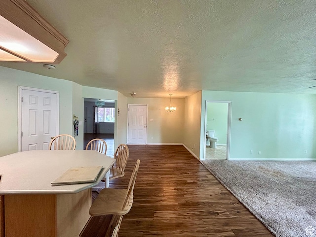 dining area featuring a textured ceiling, a chandelier, dark wood-style flooring, and baseboards
