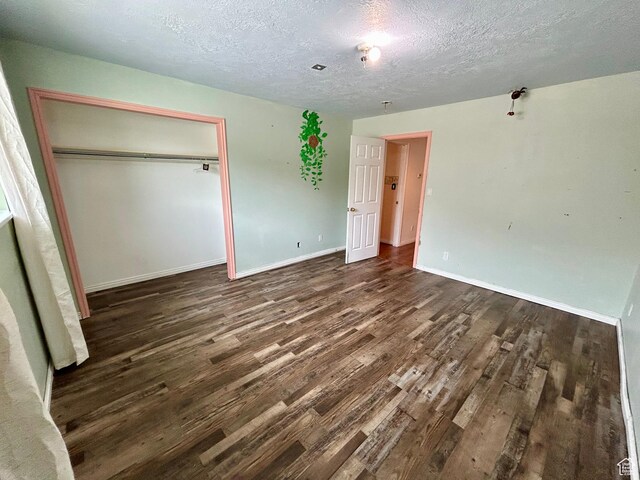 unfurnished bedroom featuring dark wood finished floors, a textured ceiling, a closet, and baseboards