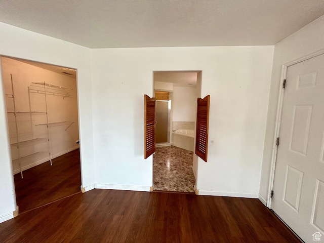 unfurnished bedroom with wood finished floors, baseboards, and ensuite bath