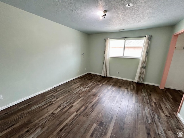 unfurnished bedroom featuring dark wood finished floors, a textured ceiling, and baseboards