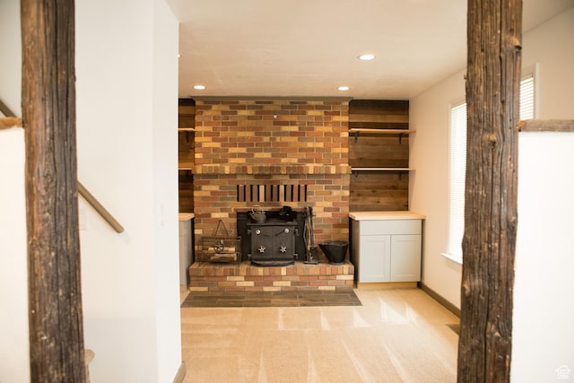 unfurnished living room featuring a wood stove, recessed lighting, carpet, and baseboards