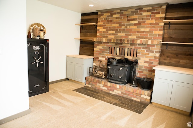 unfurnished living room with a wood stove, light carpet, baseboards, and recessed lighting