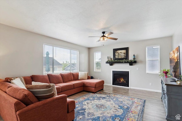 3191 N 1500 E, Layton, UT 84040 - living area with wood finished floors, a glass covered fireplace, a ceiling fan, and baseboards