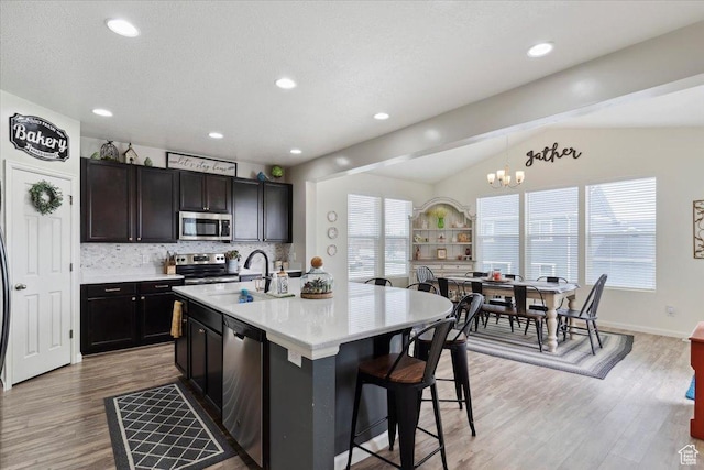 3191 N 1500 E, Layton, UT 84040 - kitchen with appliances with stainless steel finishes, a sink, vaulted ceiling, tasteful backsplash, and light wood-type flooring