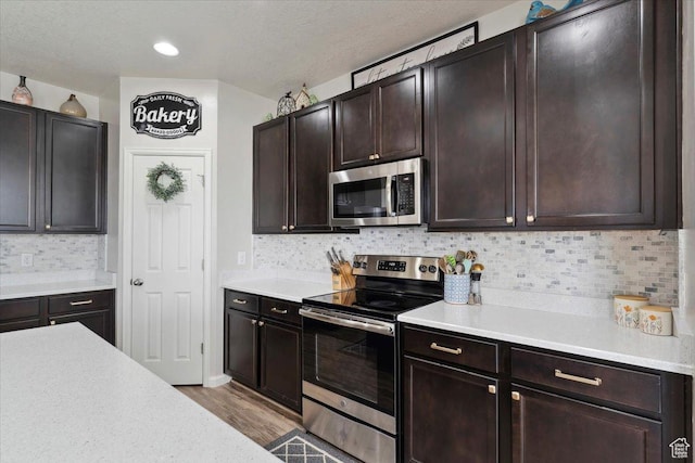 3191 N 1500 E, Layton, UT 84040 - kitchen featuring appliances with stainless steel finishes, light countertops, wood finished floors, and decorative backsplash