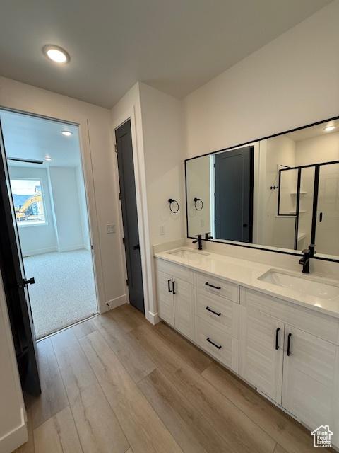 bathroom with wood finished floors, double vanity, and baseboards