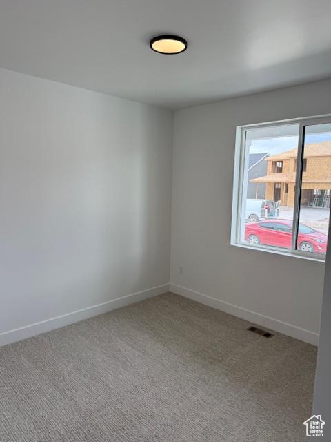 carpeted empty room featuring baseboards