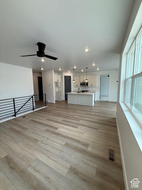 unfurnished living room with recessed lighting, light wood finished floors, baseboards, and ceiling fan