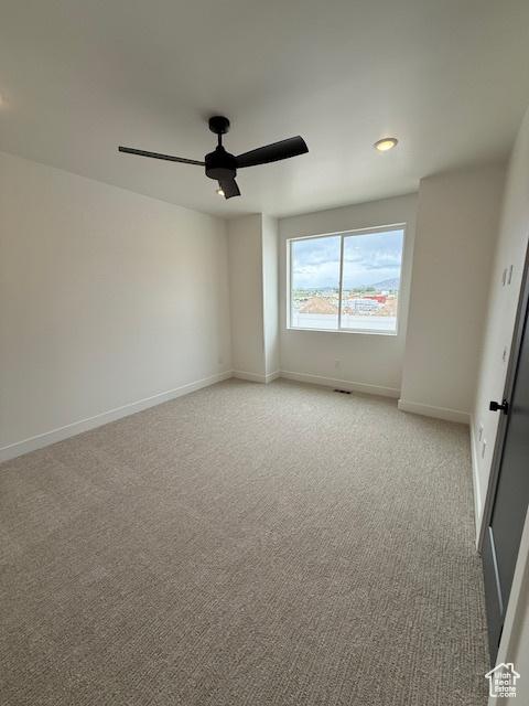 unfurnished room with light carpet, a ceiling fan, and baseboards