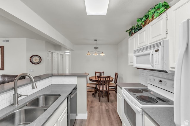 kitchen with white appliances, a sink, decorative backsplash, light wood-style flooring, and white cabinetry