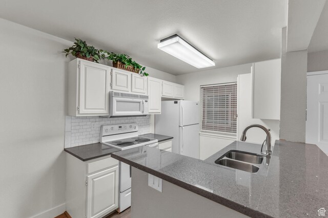 kitchen featuring white appliances, a sink, white cabinetry, decorative backsplash, and dark stone countertops