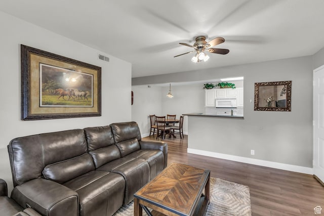 living area featuring a ceiling fan, wood finished floors, and baseboards