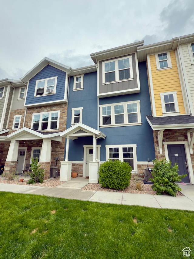 multi unit property with stone siding, a front yard, and stucco siding