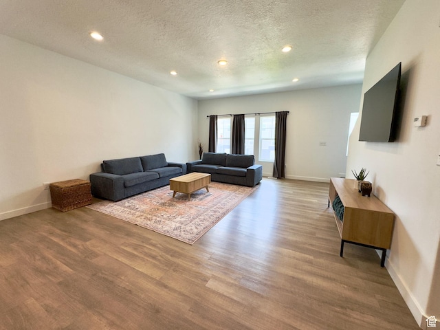 living room featuring a textured ceiling, wood finished floors, recessed lighting, and baseboards