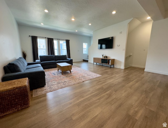 living area featuring wood finished floors, recessed lighting, baseboards, and a textured ceiling