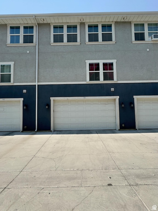 rear view of house featuring a garage, stucco siding, and driveway