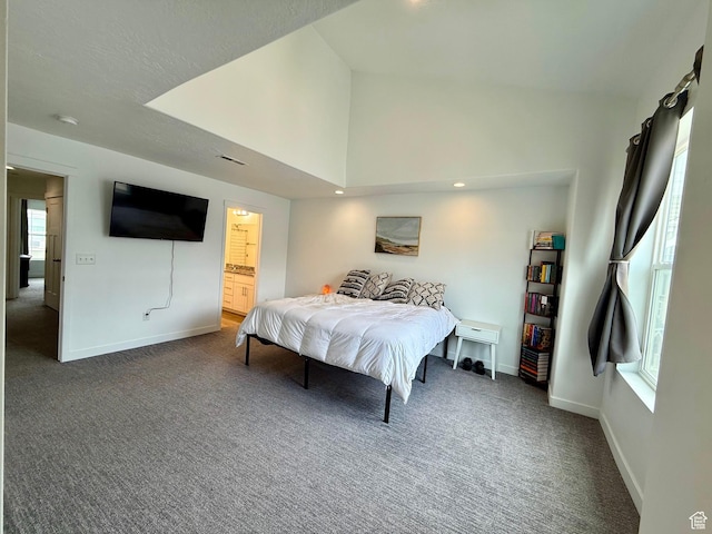 carpeted bedroom featuring baseboards, lofted ceiling, and ensuite bathroom