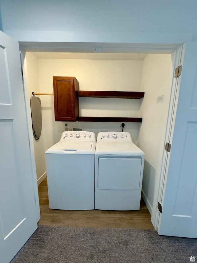 laundry area with washing machine and dryer, baseboards, dark wood-type flooring, and cabinet space