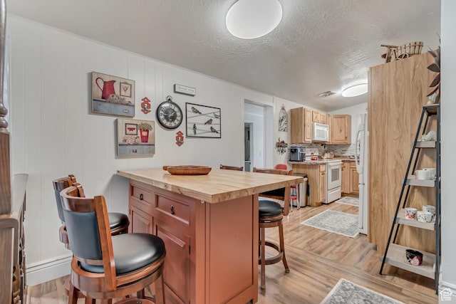 3238 S Maple Way, West Valley City, UT 84119 - kitchen with white appliances, a breakfast bar, wood counters, light wood-style floors, and a textured ceiling