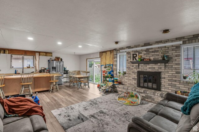926 N 400 E, American Fork, UT 84003 - living area with light wood-style flooring, a textured ceiling, a brick fireplace, and recessed lighting