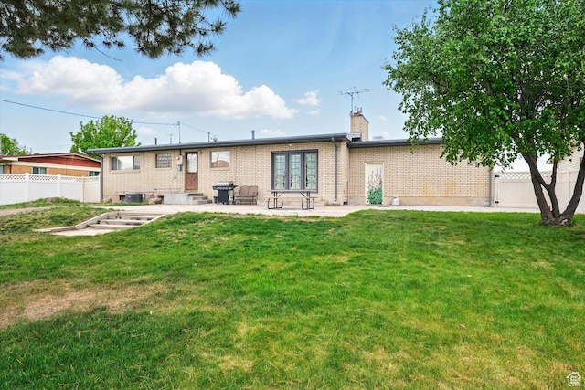 rear view of property featuring a chimney, entry steps, brick siding, a patio area, and french doors