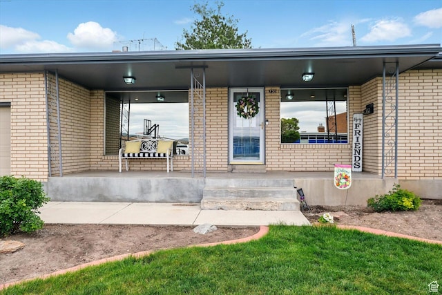 doorway to property with a porch and brick siding