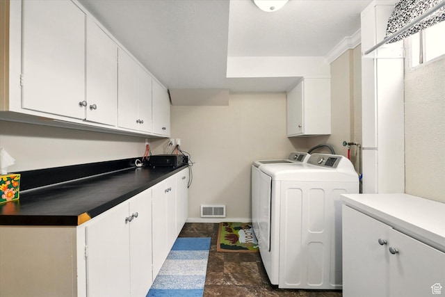 clothes washing area with cabinet space, washing machine and dryer, and dark stone finish flooring