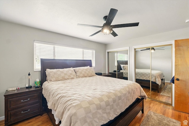 bedroom with two closets, light wood-type flooring, and a ceiling fan