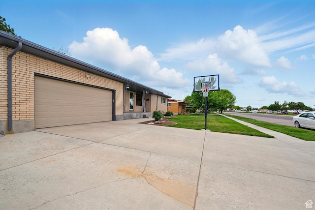 view of front facade featuring concrete driveway, brick siding, a garage, and a front lawn