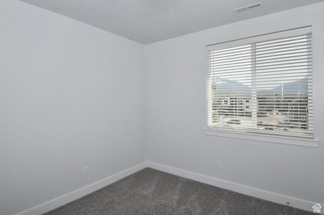 empty room featuring dark carpet, plenty of natural light, and baseboards