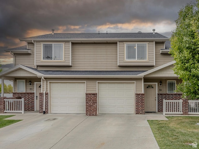 townhome / multi-family property featuring covered porch, brick siding, and a garage