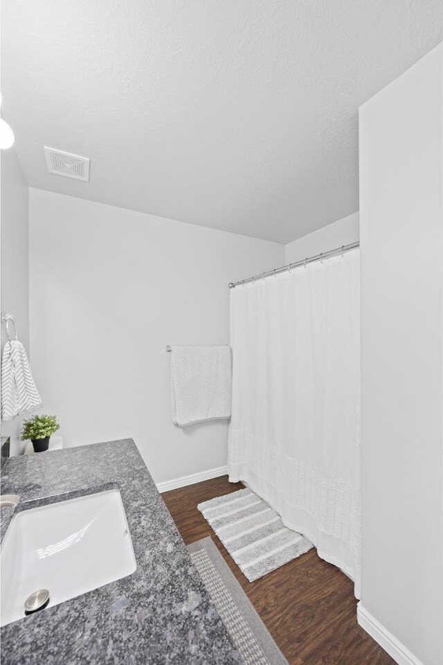 bathroom featuring wood finished floors, baseboards, a shower with curtain, and vanity