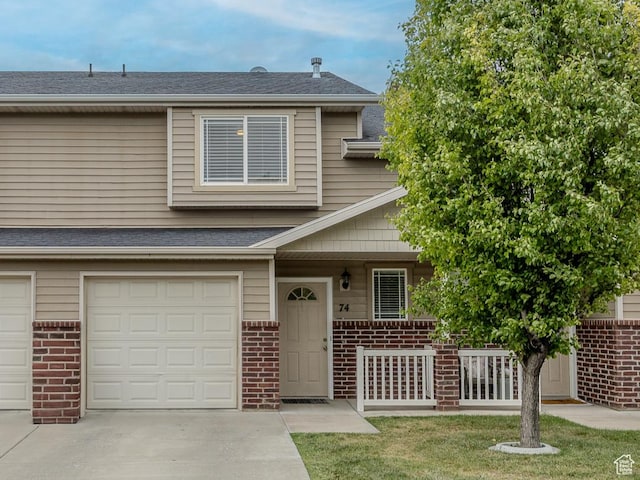 multi unit property with brick siding, covered porch, a garage, and driveway