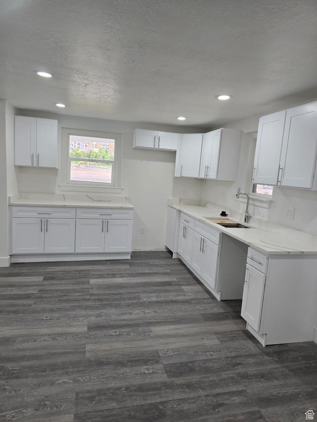 kitchen with a sink, white cabinetry, recessed lighting, dark wood-style floors, and a textured ceiling