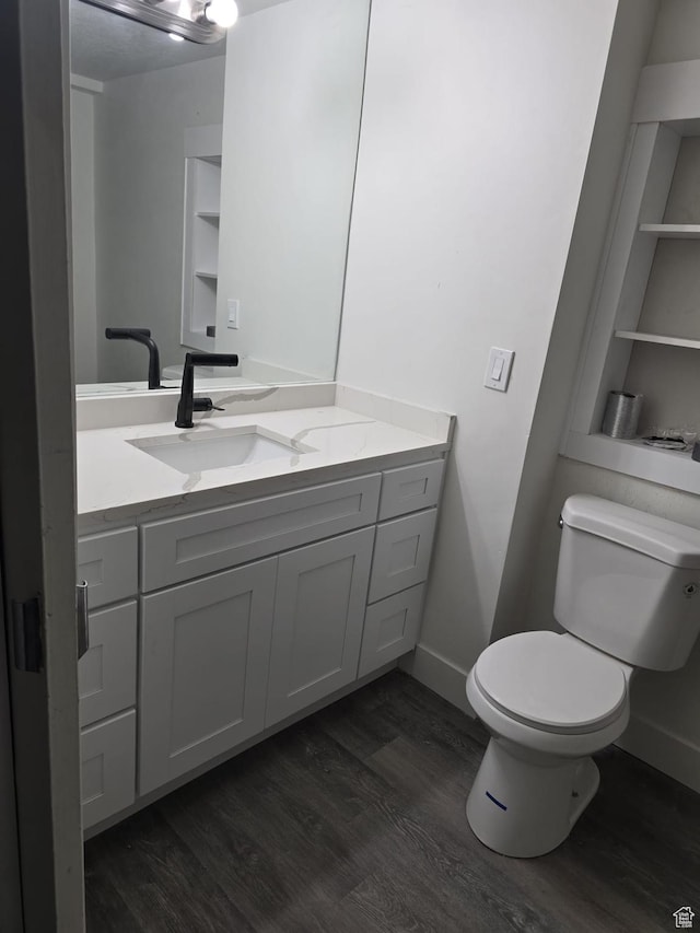 bathroom with wood finished floors, toilet, vanity, and baseboards
