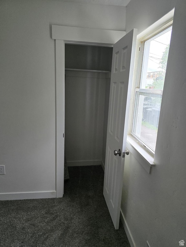 unfurnished bedroom featuring dark colored carpet, baseboards, and a closet