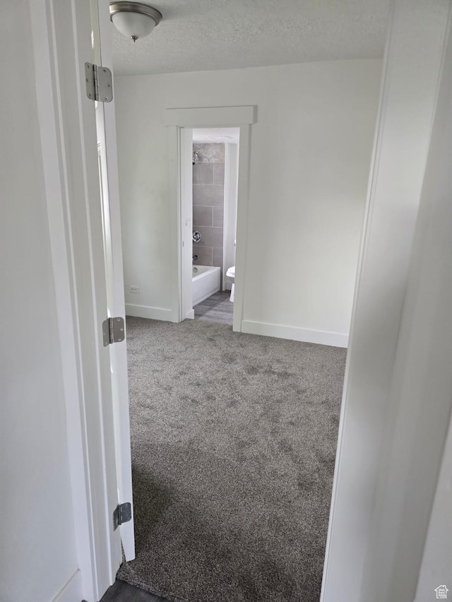 carpeted empty room with baseboards and a textured ceiling