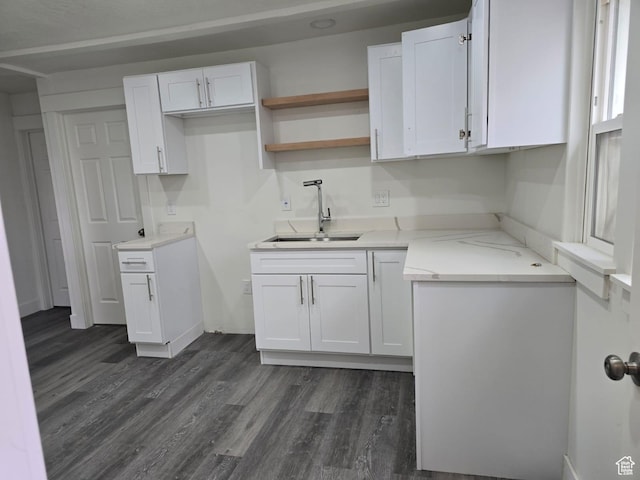 kitchen featuring a sink, white cabinetry, dark wood-type flooring, and baseboards