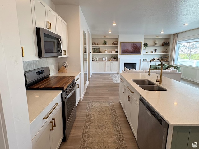 3452 W Pond Dr S, Lehi, UT 84043 - kitchen featuring stainless steel appliances, a sink, a fireplace, wood finished floors, and a textured ceiling