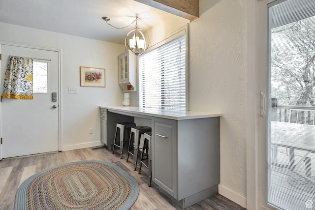 entryway featuring light wood-type flooring, a chandelier, a textured wall, and baseboards