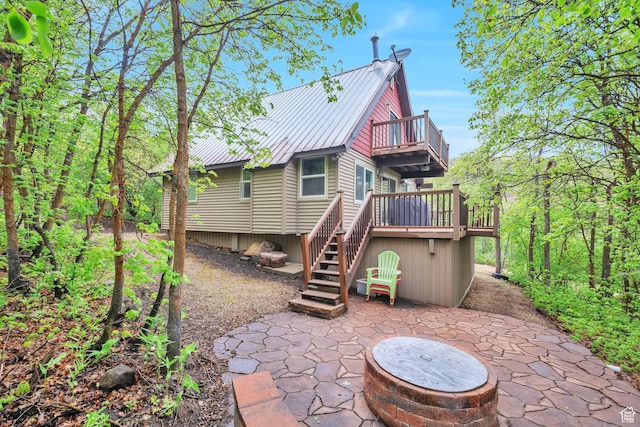 rear view of house with a patio, a balcony, stairs, metal roof, and a deck