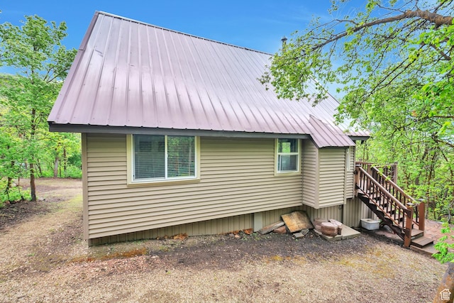 view of side of home featuring metal roof and stairway