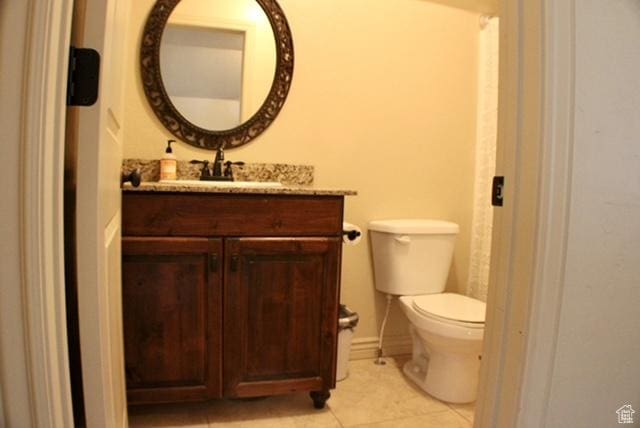 half bathroom featuring vanity, tile patterned floors, and toilet