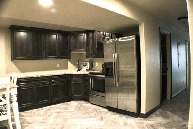 kitchen featuring appliances with stainless steel finishes, a sink, light countertops, and baseboards